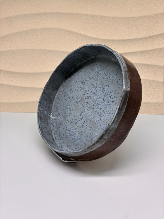 The Skystone Plate embodies a serene balance between earth and air. Its exterior, crafted in rich, unglazed brown clay, contrasts with a delicately speckled blue glaze that evokes the texture of weathered stone beneath a clear sky. The soft matte finish and gentle imperfections highlight the handmade nature of the piece, while the cool tones and subtle speckles bring a quiet sense of depth and calm. Ideal for both functional and decorative use.