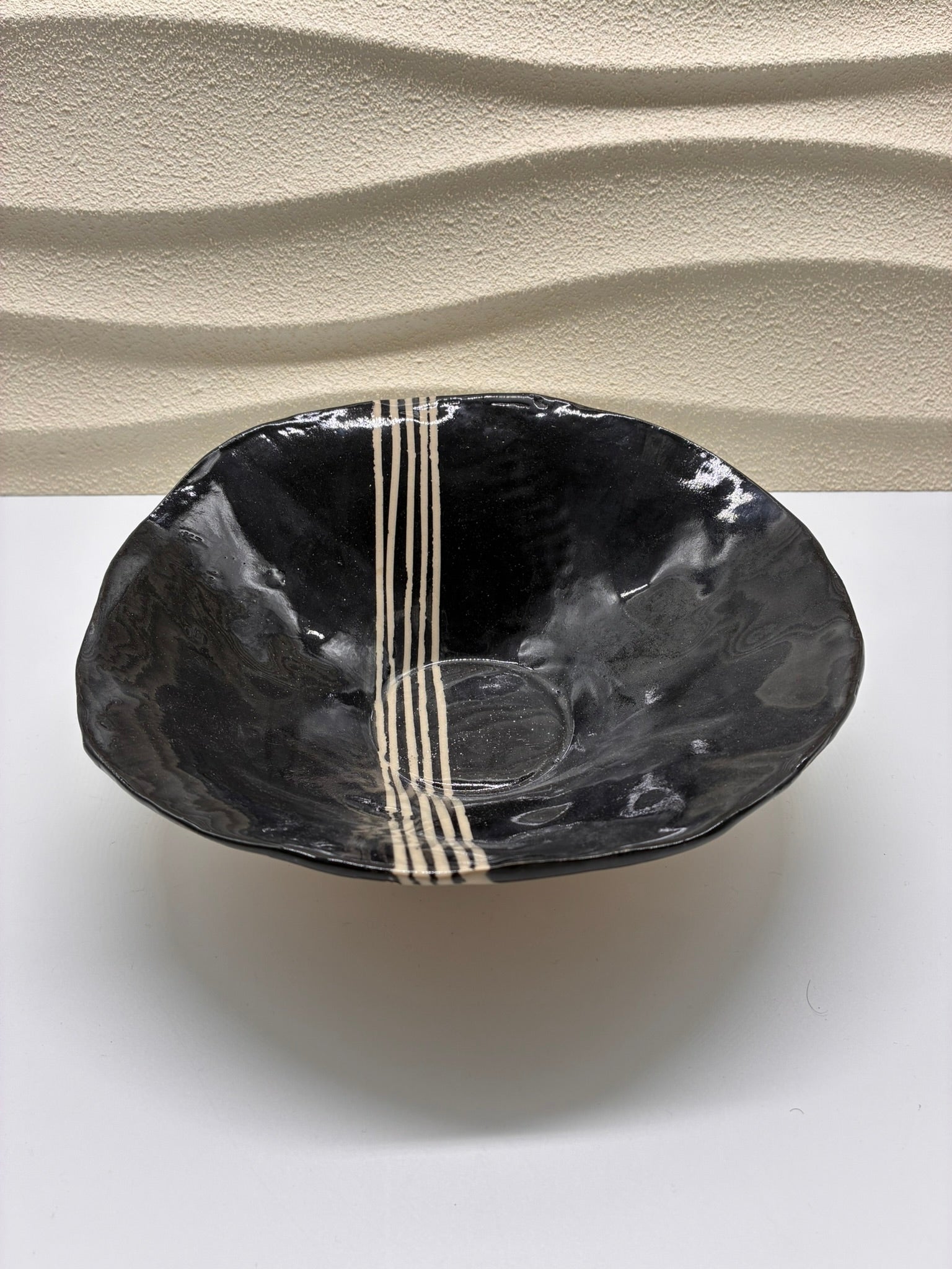 Elegant and modern, the Luna Lines Ceramic Bowl combines deep black glaze with hand-painted ivory stripes for a minimalist yet striking design. Its organic form and glossy finish highlight the beauty of handcrafted pottery. Perfect for serving, display, or adding a contemporary touch to your dining experience.