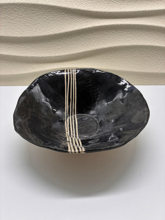 Elegant and modern, the Luna Lines Ceramic Bowl combines deep black glaze with hand-painted ivory stripes for a minimalist yet striking design. Its organic form and glossy finish highlight the beauty of handcrafted pottery. Perfect for serving, display, or adding a contemporary touch to your dining experience.