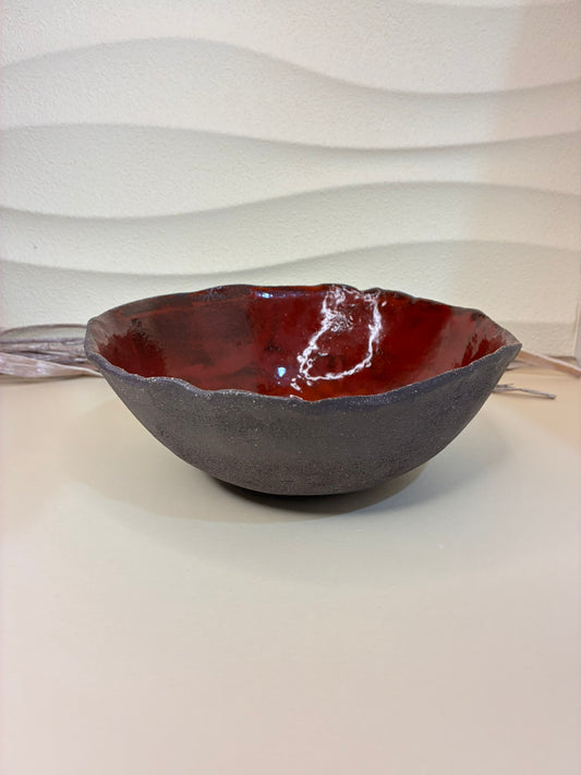 This bowl has a beautifully organic, handcrafted presence — a perfect balance between rugged earthiness and refined artistry.

Its outer surface is a deep, matte brown-black, textured like volcanic stone or dark clay. The form is slightly asymmetrical, with a softly undulating rim that gives it a natural, hand-formed character — embracing imperfection in a wabi-sabi sense.