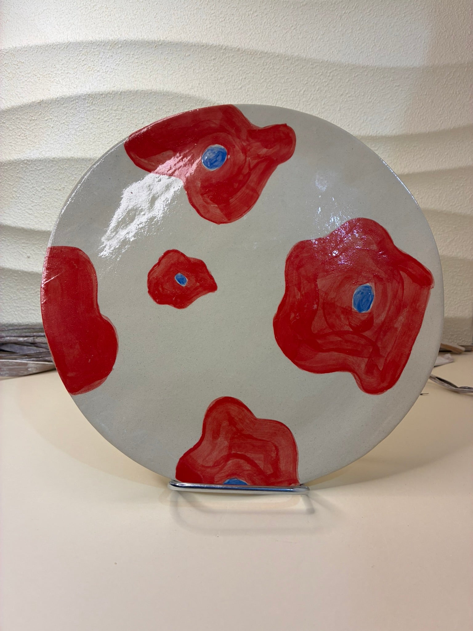 This handcrafted ceramic plate is adorned with small hand-painted red flowers, creating a delicate and lively pattern across the surface. Designed exclusively for serving, it blends artisanal craftsmanship with a soft decorative touch, adding warmth and character to the table.