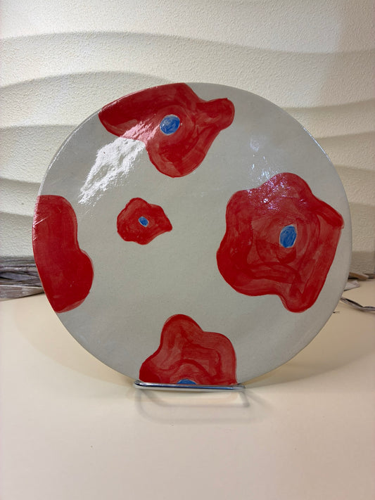 This handcrafted ceramic plate is adorned with small hand-painted red flowers, creating a delicate and lively pattern across the surface. Designed exclusively for serving, it blends artisanal craftsmanship with a soft decorative touch, adding warmth and character to the table.