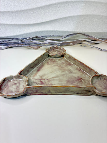 This handcrafted triangular ceramic serving piece features three integrated bowls positioned at each corner, designed for serving chips, Doritos, or snacks with dips and sauces. Its sculptural triangular form creates a playful yet refined presentation, making it ideal for sharing at gatherings or casual entertaining. Each piece is carefully handmade, with subtle variations that highlight its artisanal character. Functional, eye-catching, and thoughtfully designed, it brings both style and practicality to th