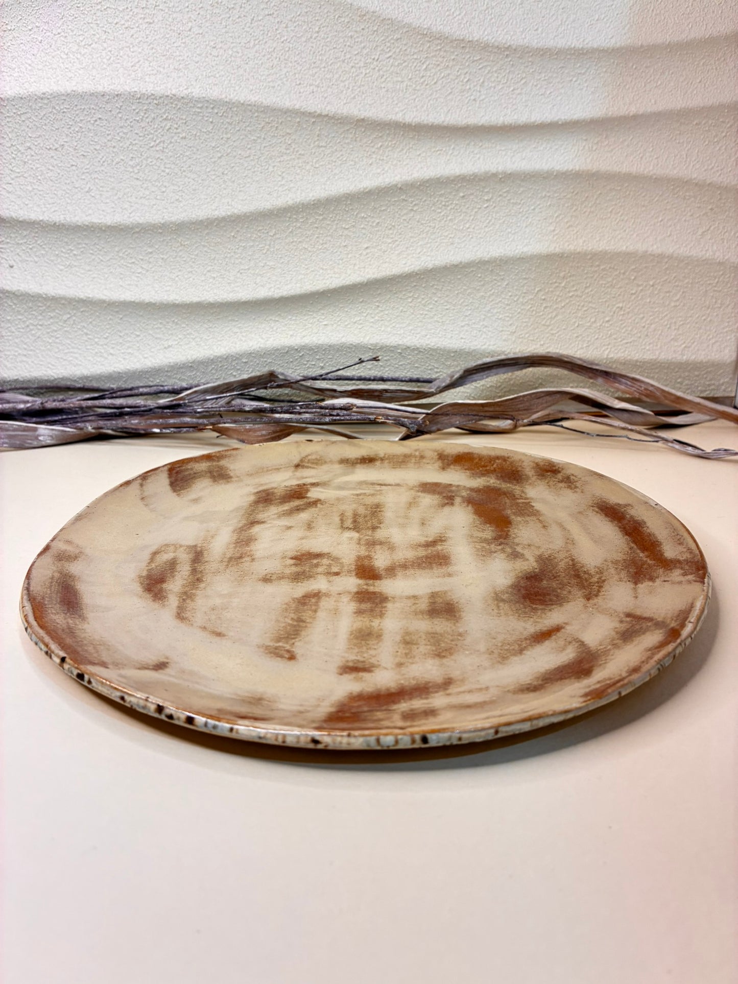 This handcrafted shallow ceramic plate features a blend of blue and light brown tones, creating a warm, earthy aesthetic with natural variation. Each plate is individually made by hand, resulting in a unique pattern and artisanal character. Designed exclusively for serving, it combines functionality with subtle, rustic elegance, adding a refined touch to any table setting.