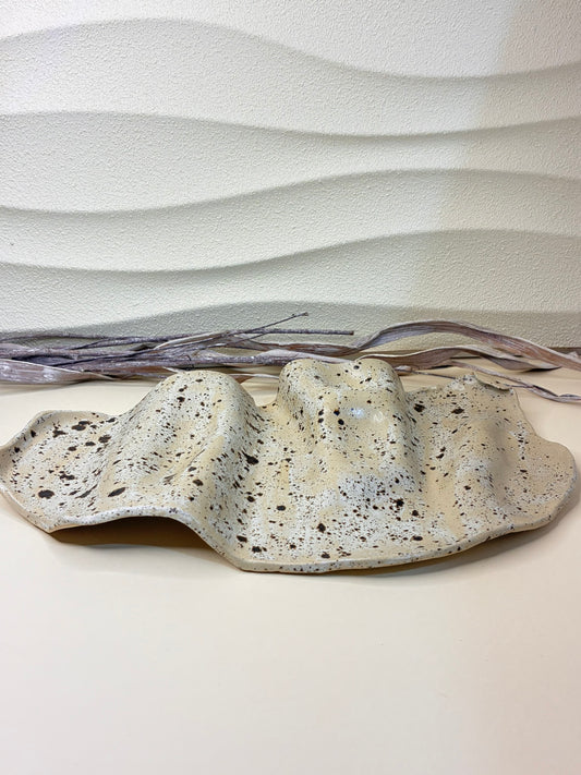 This handcrafted ceramic serving platter features a wavy, organic form and a winter wood–inspired color palette, blending soft neutral tones with natural depth and warmth. Its flowing edges and subtle surface variations highlight the handmade character of the piece. Designed for serving, it offers a refined yet earthy presence, making it ideal for presenting food with understated elegance.