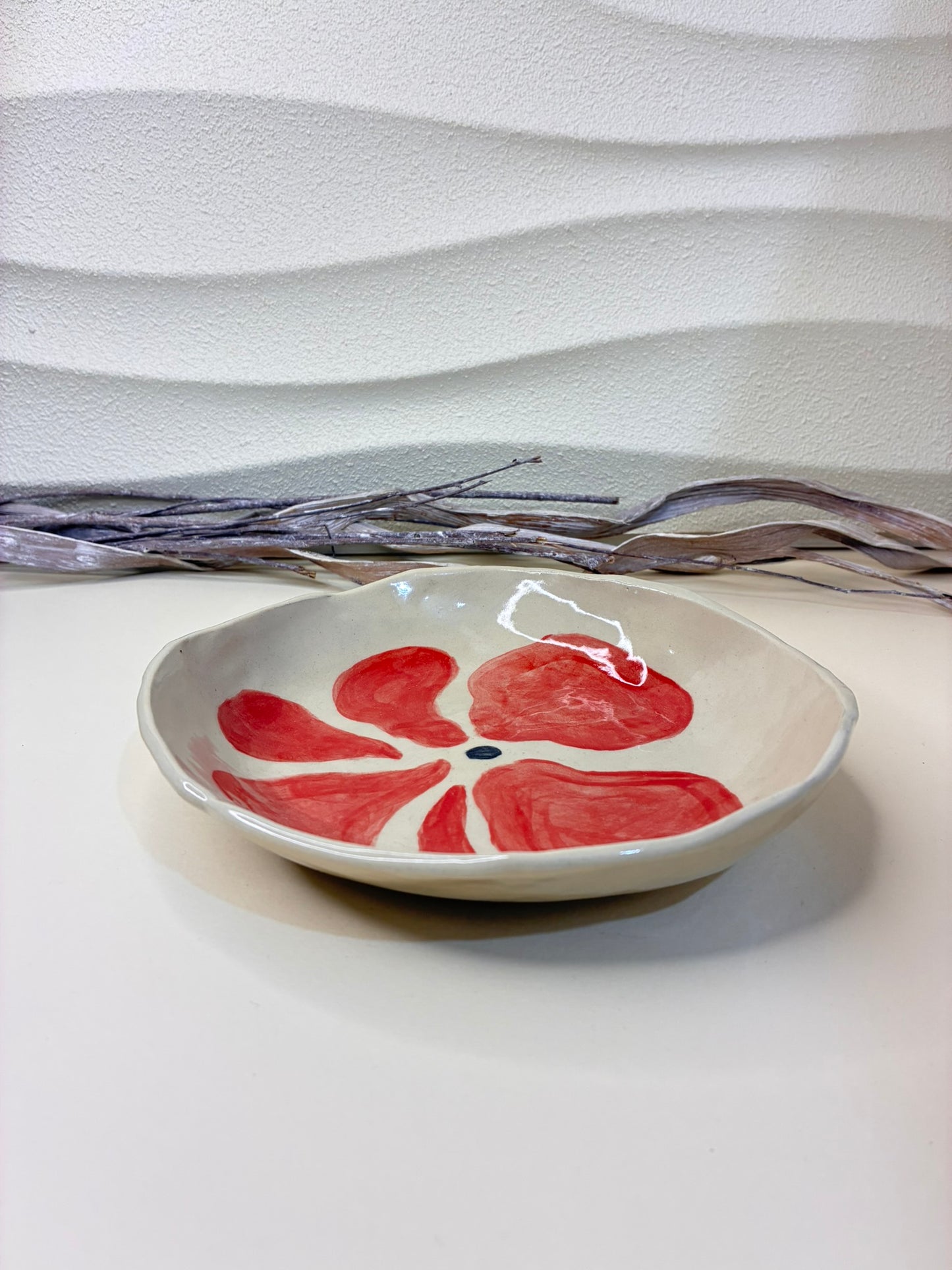 This handcrafted ceramic bowl is decorated with small hand-painted red flowers, creating a delicate and charming pattern. Each piece is individually painted by hand, making every bowl unique. Both functional and decorative, it is ideal for everyday use while adding a warm, artisanal touch to the table.