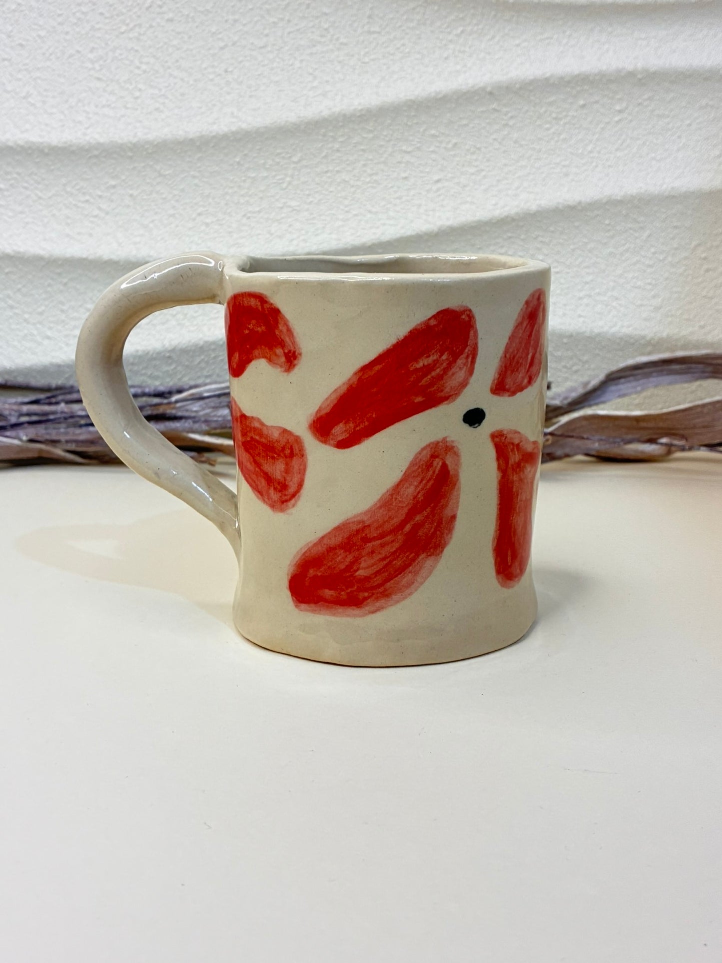 This handcrafted ceramic mug features small hand-painted red flowers, creating a charming and delicate pattern. Each piece is individually painted by hand, making every cup unique. Designed for everyday use, it combines functionality with artisanal elegance, adding warmth and character to your coffee or tea moments.