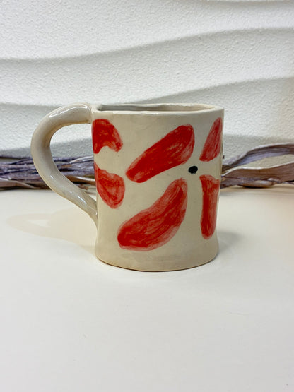 This handcrafted ceramic mug features small hand-painted red flowers, creating a charming and delicate pattern. Each piece is individually painted by hand, making every cup unique. Designed for everyday use, it combines functionality with artisanal elegance, adding warmth and character to your coffee or tea moments.