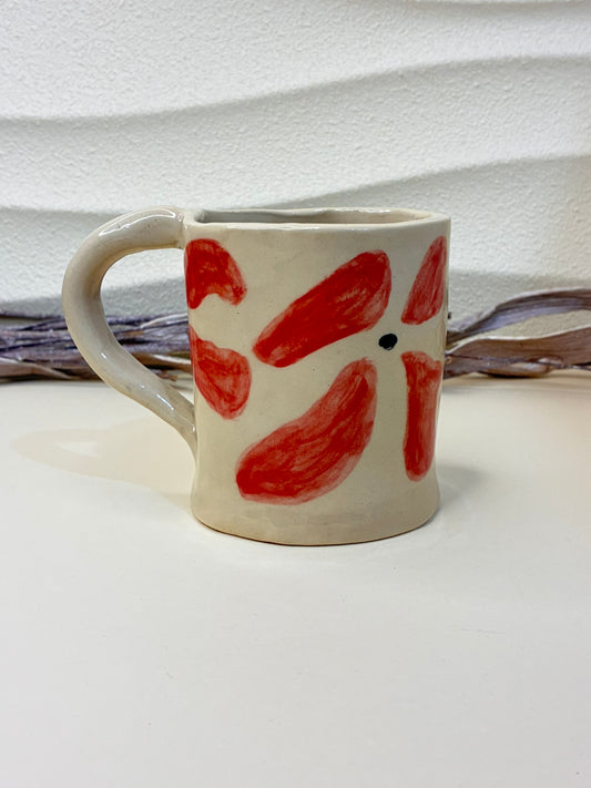 This handcrafted ceramic mug features small hand-painted red flowers, creating a charming and delicate pattern. Each piece is individually painted by hand, making every cup unique. Designed for everyday use, it combines functionality with artisanal elegance, adding warmth and character to your coffee or tea moments.
