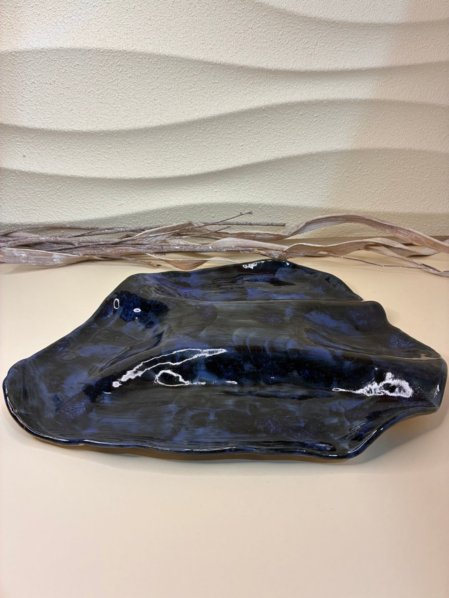 This handcrafted irregular platter features an organic, freeform shape that highlights its artisanal craftsmanship. Perfectly suited for both functional and decorative use, it can hold charcuterie, nuts, or appetizers, while also serving as a decorative base for candles, stones, or other accents. Each piece is unique, with subtle variations in texture and form that celebrate its handmade character. Combining practicality with sculptural elegance, it brings style and versatility to any table or display.