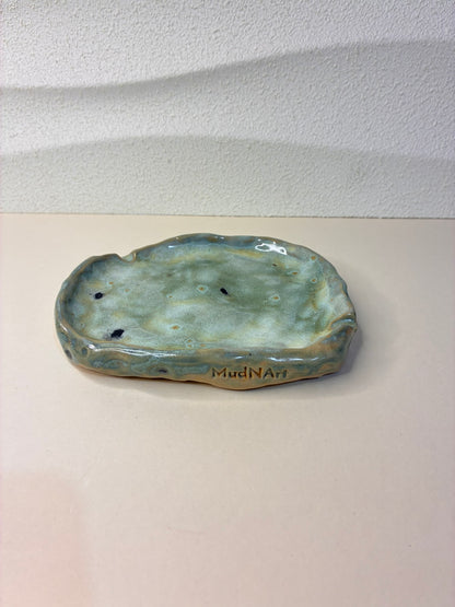 This handcrafted shallow tray serves as a discreet ashtray while also doubling as a jewelry holder. Its minimalist design and subtle, elegant form make it a versatile addition to any table, dresser, or shelf. Each piece is carefully handmade, with unique variations that highlight its artisanal character, combining functionality and refined style in one.