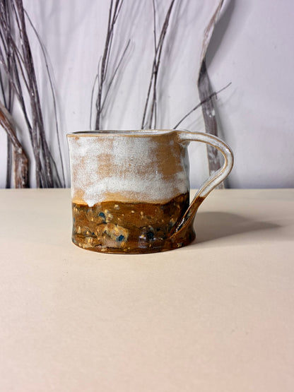 Handmade ceramic cup featuring a balanced two-tone design in soft cream and warm brown. The natural color division highlights the raw beauty of the clay and the hand-crafted process, with subtle variations that make each piece unique. Earthy, minimal, and timeless, this cup brings warmth and simplicity to everyday coffee or tea rituals.