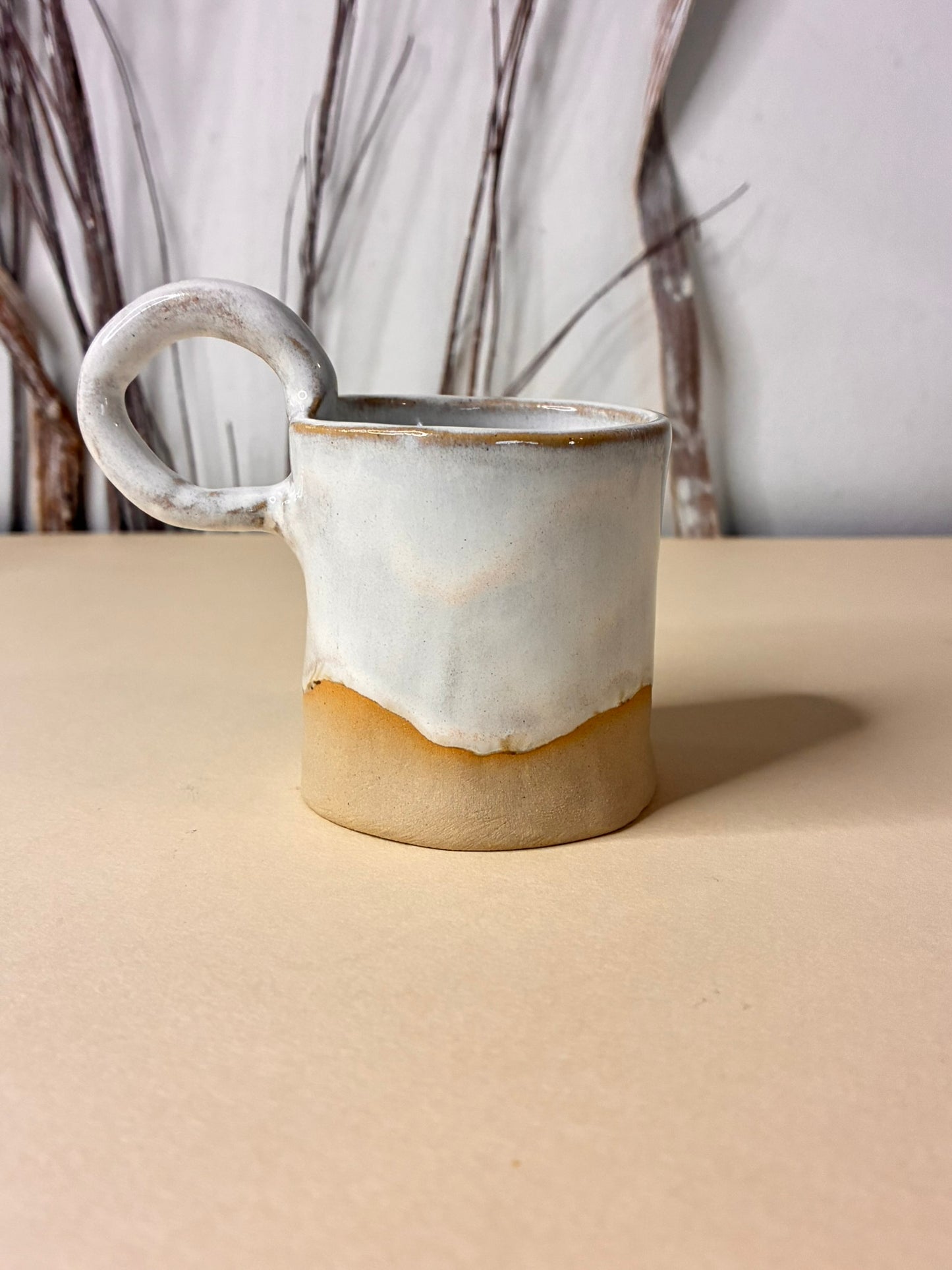 This handcrafted stoneware cup features a smooth creme glaze and showcases the beauty of artisanal pottery. Each cup is uniquely made by hand, with subtle variations that highlight its character.  It’s perfect for enjoying coffee or tea while adding a warm, timeless touch to your table.