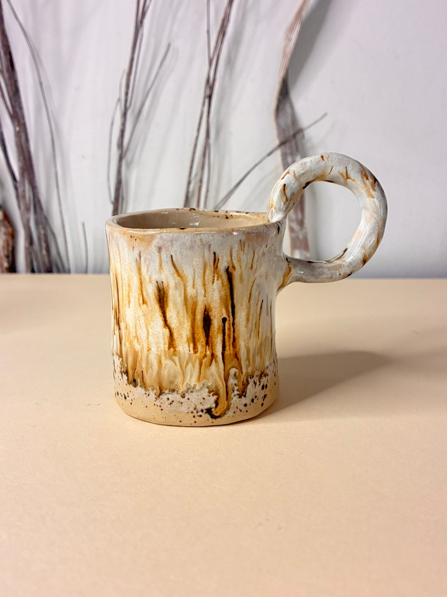 Handmade ceramic cup featuring a flowing glaze effect where warm chocolate tones appear to melt and drip over a soft cream base. Each piece is individually finished, allowing the glaze to move freely and create organic, one-of-a-kind patterns. Earthy, tactile, and expressive, this cup captures motion and warmth in a functional ceramic form.