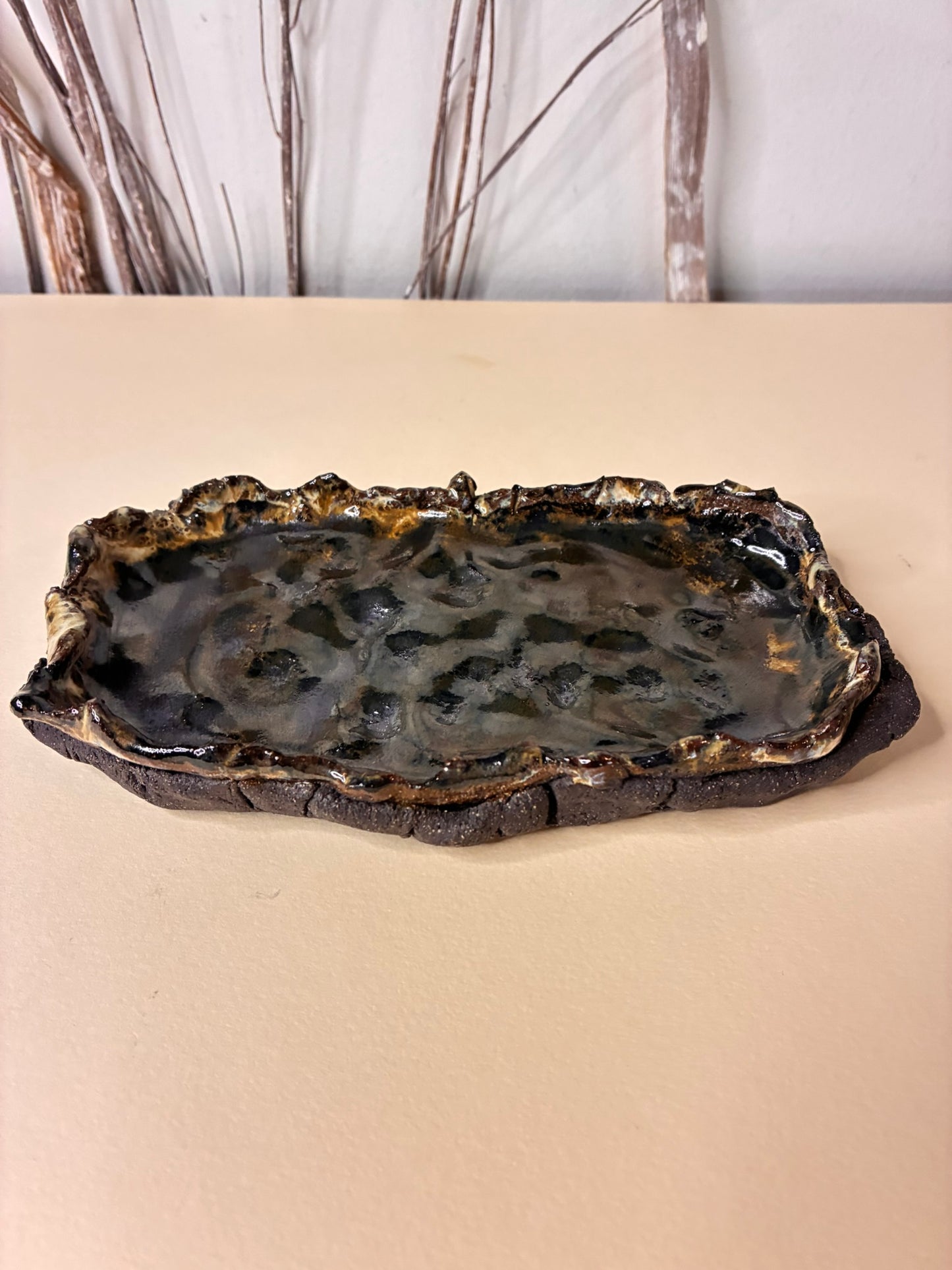 This handcrafted stoneware tray features a volcanic stone-inspired finish, giving it a natural, earthy texture and a striking look. Designed to be multi-functional, it can be used as an ashtray, a jewelry holder, or a small serving dish. Each piece is carefully made by hand, with subtle variations that highlight its artisanal character. Decorative and functional, it brings a bold, elegant touch to your home while keeping your essentials organized in style.